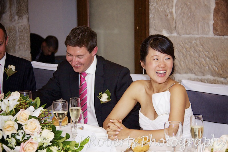 Bride and groom laughing at speeches at the reception - wedding photography sydney
